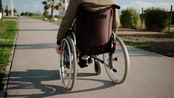 Gehen eines Rollstuhlfahrers an sonnigen Tagen im Freien, Rückansicht