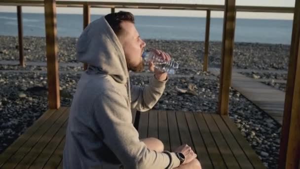 Человек утоляет жажду прохладной водой после спортивных тренировок — стоковое видео