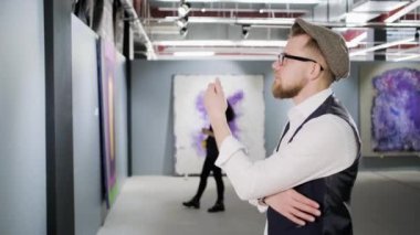 Sanat galerisindeki tuvali inceleyen adam.