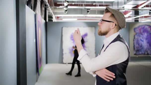 Mannen undersöker duken i konstgalleriet — Stockvideo