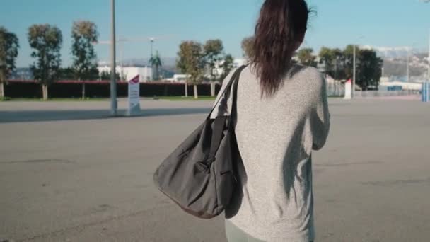 Mujer joven con bolsa de gimnasio caminando por la calle — Vídeos de Stock