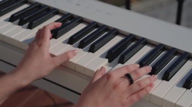 Genç bayan Musisian 'ın parmakları piyano tuşlarına dokunup melodi çalıyor.