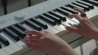 Genç kadın elleri elektrikli piyanoda oynuyor.