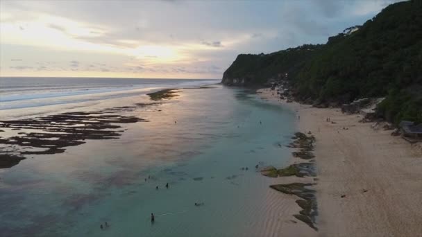 Vista aérea da costa do oceano com veranistas ao pôr do sol em Bali — Vídeo de Stock