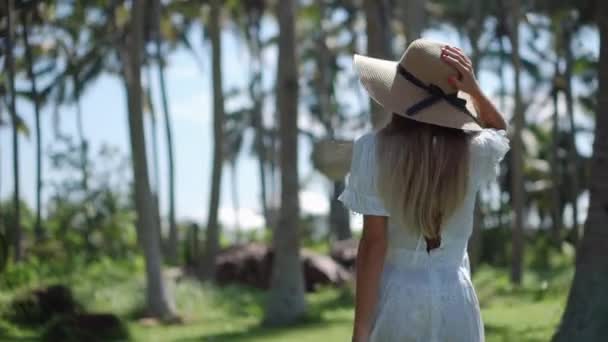 Meisje geniet van de wandeling tussen tropische palmen — Stockvideo