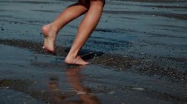 Deniz kıyısında koşan genç kadının bacakları, yakın plan.