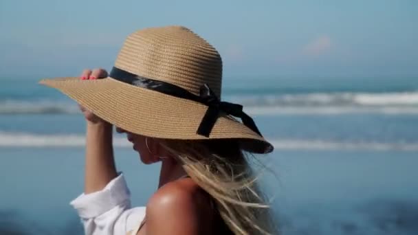 Fille gaie en bikini et chapeau de soleil marchant le long de la côte de l'océan — Video