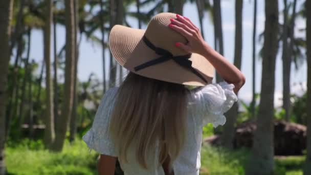Chica vacacionista dando un paseo por el bosque de palmeras tropicales y disfrutando del calor del verano — Vídeo de stock