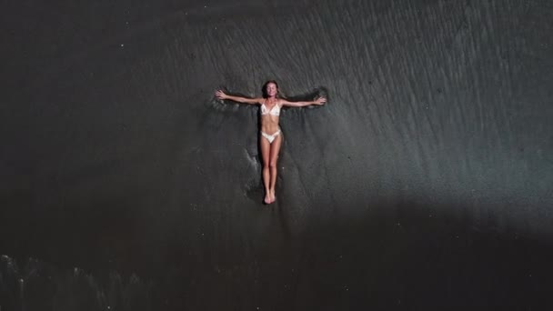 Kvinna på svart sand strand på Bali, antenn utsikt — Stockvideo