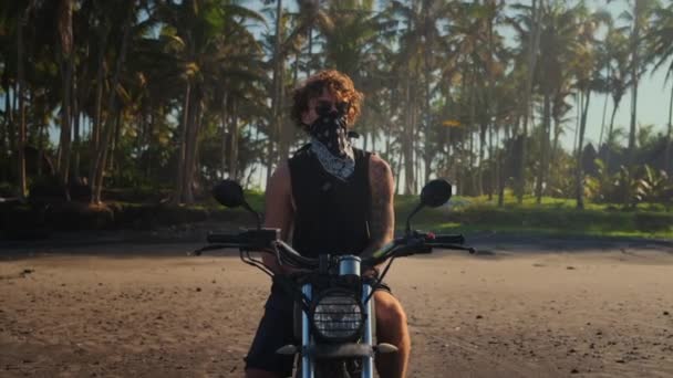 Gedurfde getatoeëerde motorrijder op tropisch strand — Stockvideo