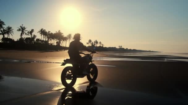 Motard est à cheval sur la plage de la mer au coucher du soleil — Video