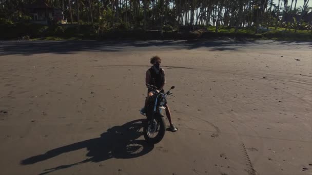 Hombre sentado en silla de montar de una bicicleta y mirando el océano — Vídeo de stock