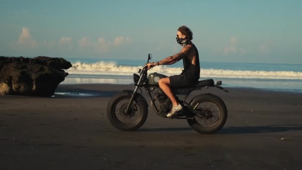 Bisikletli bir yolcu okyanus sörf hattındaki kayalıklar boyunca araba sürer. — Stok video