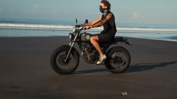 Одинокая поездка байкера по океанскому пляжу — стоковое видео