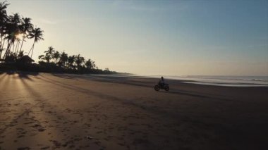 Hafif motosikletli bir motorcu deniz kıyısında daireler çiziyor.