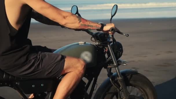 Getatoeëerde biker rijden op het strand — Stockvideo