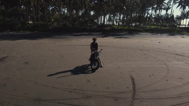 Zdjęcie lotnicze motocyklisty na tropikalnej plaży — Wideo stockowe