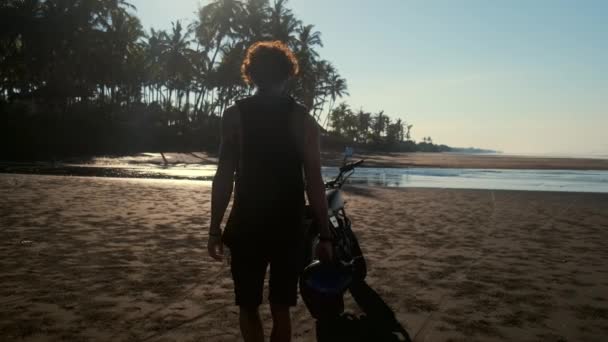 motocyklista sedí na motorce na pláži oceánu