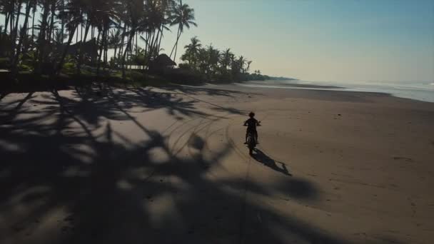 Motocyklista jedzie przez pustą plażę, strzał z powietrza — Wideo stockowe
