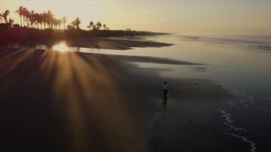 Adam okyanus sahilinde motosiklet sürüyor, hava manzaralı.