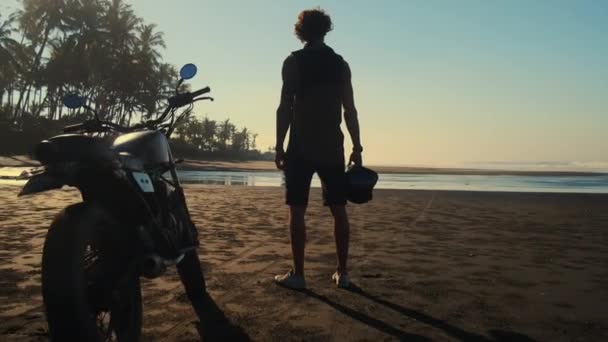 Lone bike rider az óceán partján naplementekor — Stock videók
