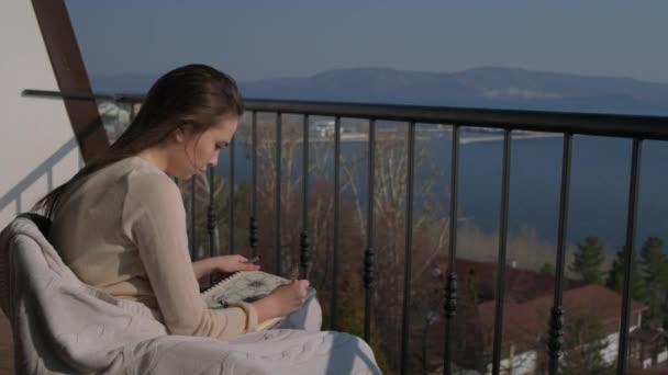 Ung dam konstnär arbetar med skissbok på balkong — Stockvideo