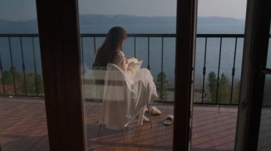 Genç kadın sanatçı denizin üstünde verandada portre üzerinde çalışıyor.