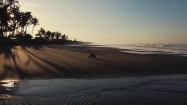 Gezgin okyanus sahilinde bisiklet sürüyor. Havadan çekilmiş.