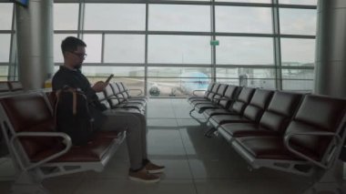 Havaalanının kalkış salonu, erkek yolcu bekliyor.