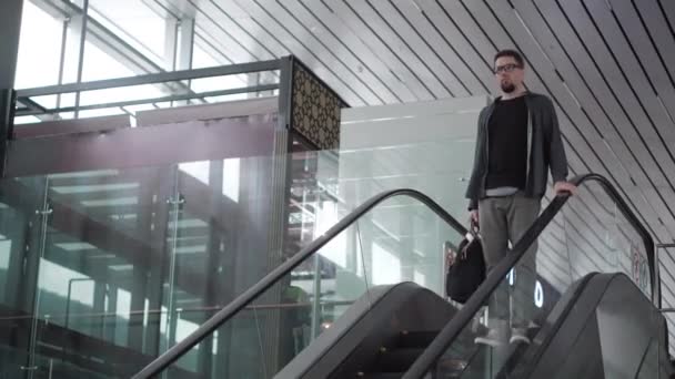 Voyageur homme sérieux descendant sur l'escalator dans le grand aéroport — Video