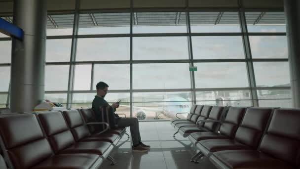 Niemand wartet gern. Mann tötet Zeit mit Handy am Flughafen — Stockvideo