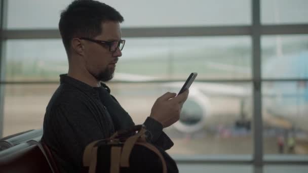 Hombre con smartphone está esperando el embarque en el aeropuerto — Vídeo de stock