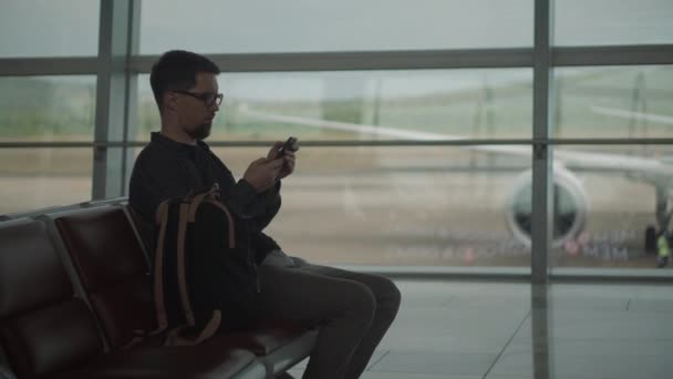 Hombre enviando mensajes a amigos antes del vuelo — Vídeo de stock