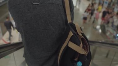 Alışveriş merkezinde yürüyen merdivendeki adam.