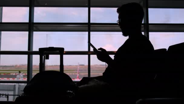 携帯電話で空港での彼のフライトを待っている乗客 — ストック動画