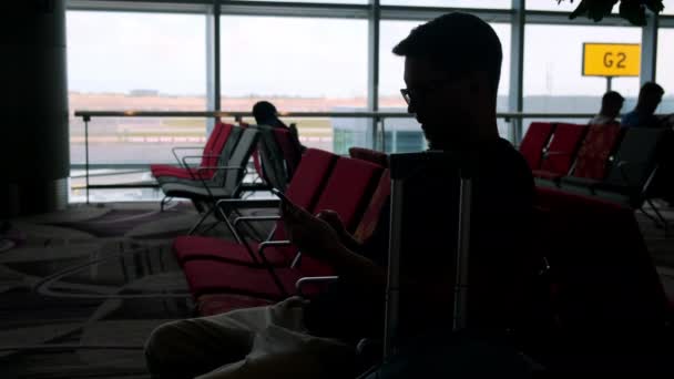 Mann mit Zelle wartet in Flughafen-Lounge auf verspäteten Flug — Stockvideo