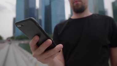 Bilinmeyen gezgin büyük bir şehrin caddesinde akıllı telefondan mesaj atıyor.