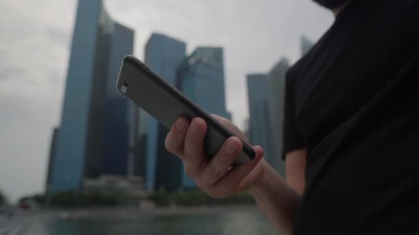 Teléfono inteligente en la mano del hombre en la gran ciudad, rascacielos en el fondo — Vídeo de stock
