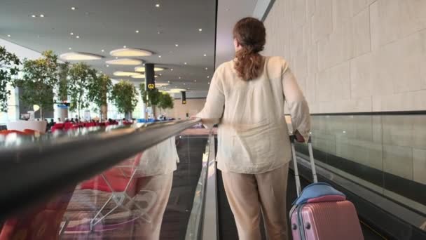 Frau auf fahrendem Gehweg am Flughafen — Stockvideo