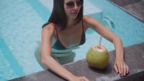 Sexy Frau entspannt sich im Pool mit Cocktail — Stockvideo