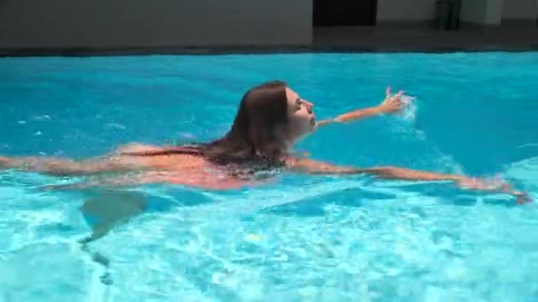 Το όμορφο κορίτσι απολαμβάνει το κολύμπι σε μια ανοιχτή πισίνα. — Αρχείο Βίντεο