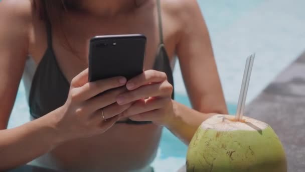 Женщина болтает по смартфону в бассейне, крупным планом — стоковое видео