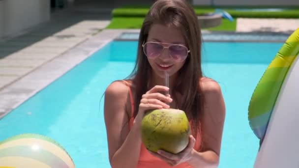Elegante joven bebiendo cóctel de frutas tropicales en la piscina del resort — Vídeos de Stock