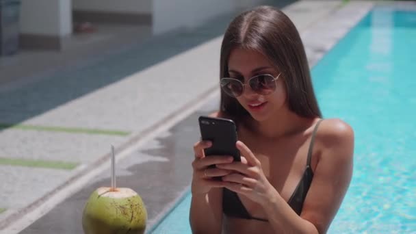 Modello femminile è a riposo in piscina con telefono — Video Stock
