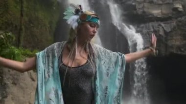 Etnik renkli giyinmiş konsantre genç kadın, akıntıya karşı meditasyon yapıyor.