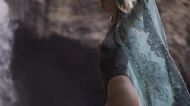 Seksi vücutlu kadın şelalenin yanında poz veriyor.