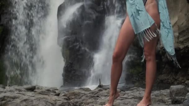 Довгонога струнка молода жінка в екзотичному одязі позує біля водоспаду в містичному образі — стокове відео
