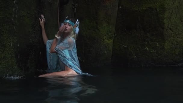 Attractive young woman enjoying slow dance in water in a dark waterfall cave — Stock Video