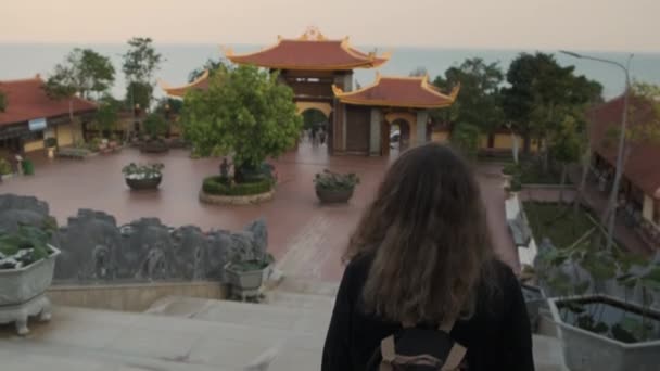 Неизвестная женщина идет по территории буддийского монастыря — стоковое видео