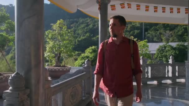 Jongeman genieten van een wandeling door terras van boeddhistische tempel — Stockvideo